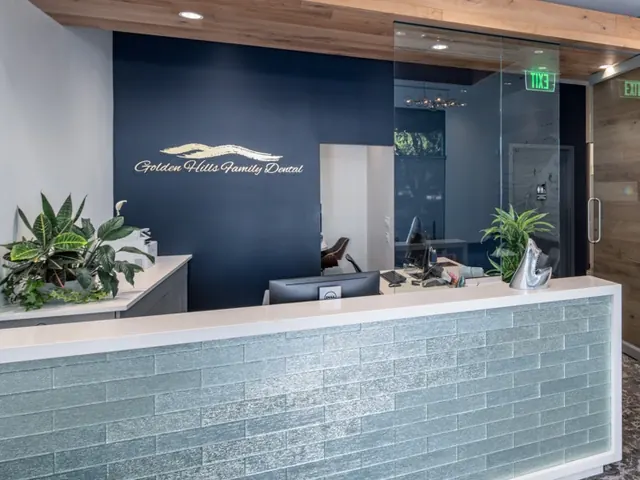The reception desk at Golden Hills Family Dental, with the gold logo on a navy wall.